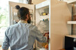 © Svitlana - Young man, professional cook in apron taking ingredients out of the fridge while getting ready to prepare a meal, standing in the kitchen. Cooking at home concept