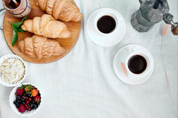 Two coffee cups and Italian coffee maker with croissant and fruits