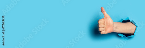 Fotografía Male hand makes a hand up gesture on a blue background
