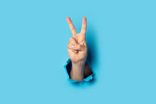 Male Hand Makes A Two Fingers Up Greeting Gesture On A Blue Background. Banner