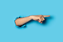 Hand Points To Something On A Blue Background. Gesture Look At This, Pay Attention