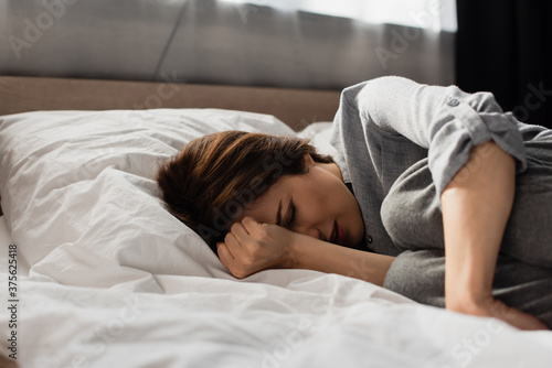Cuadros en Lienzo exhausted woman suffering from pain and touching head while lying on bed