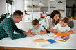 © JustLife - Parents helping the kids with their homework. Litlle boys learning at home..