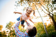 © fesenko - young father raises his cheerful daughter high up with his hands