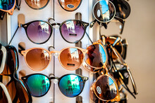 Closeup Of Many Modern Colorful Sunglasses In Outdoor Market Shop Store Rack In Rome, Italy Outside With Reflection