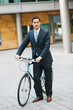 © Ivo de Bruijn/Stocksy - Business man in suit standing next to his bike