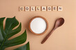 collagen powder in a wooden bowl, spoon, peach background, top view, green leaf, lettering