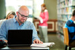 © Sean Locke Photography/Stocksy - Library: Adult Male Uses Laptop in Library