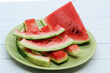 Close-up of triangular piece watermelon and watermelon rind on on a light green flat plate. 