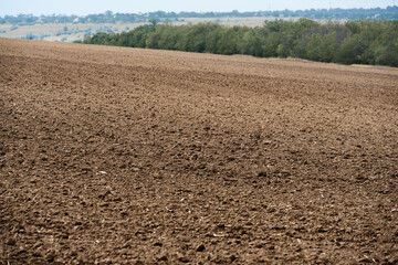 plowed field and blue sky, soil and clouds of a bright sunny day - concept of agriculture