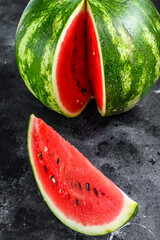 Wall Mural - Red ripe watermelon with cut-out slices. Black background. Top view