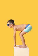 Poster - Little boy in start position on swimming block against color background