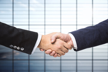 Handshake of two businessmen on the background of empty office, partnership concept, close up