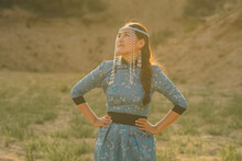 Mongolian Woman Wears National Costume In A Desert At Sunset.