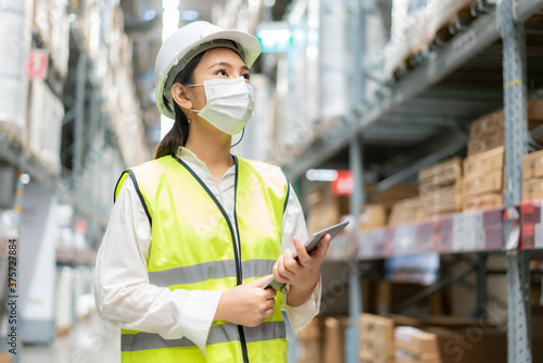 Cuadros en Lienzo Young asian woman auditor or trainee staff wears mask working during the COVID pandemic in store warehouse shipping industrial