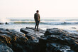 © Suzi Marshall/Stocksy - Man standing on rocks looking out to sea at sunset