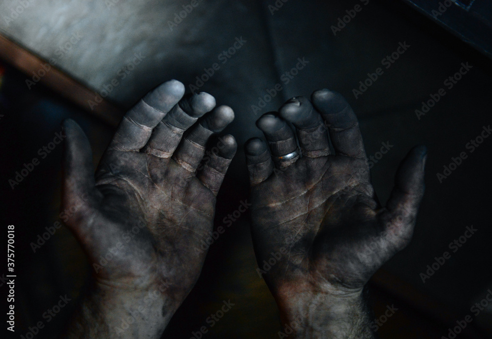 Man's hands covered in black soot
