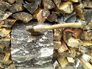 Abstract photograph of piles of natural wooden logs. Background. An axe is stuck on the big stump. Harvesting firewood for the winter. Texture. View from above. Wood for the fireplace. Birch boards.