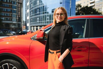 Wall Mural - Yong pretty woman standing near a big all terrain car outdoors. Driver girl in casual clothes outside her vehicle.