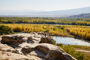 Uplistsikhe, Georgia - October 22, 2020: Tourists in a mountain reserve near ancient old city with rocks, residential and religious caves and blue sky on a Sunny summer day. Uplistsikhe city, Georgia