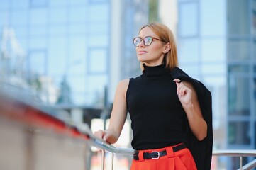 Portrait shot of the Caucasian beautiful woman office worker standing near big glass office center.