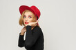 © SHOTPRIME STUDIO - Fashionable woman in red hat black blouse red lips cropped view light background emotions