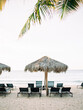 © Daniel Kim Photography/Stocksy - Thatch hut and lounge chairs