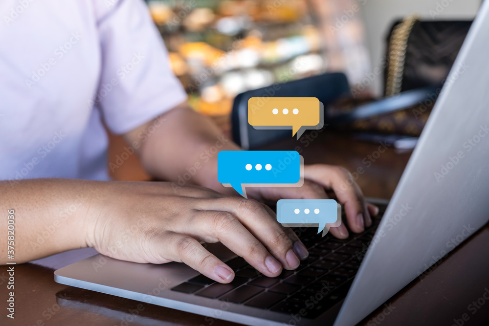 Person hand using computer laptop typing into chat, chatting conversation in chat bubble pop-up. Social media maketing concept.