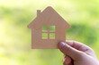 toy wooden house in hand on a light green background, Concept - buying a house on credit or mortgage, safe and affordable housing. My home is my castle. safety