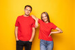 © F8  \ Suport Ukraine - Portrait of cool couple in red shirts looking at camera isolated on yellow background.