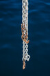 © Gabriel Tichy/Stocksy - Large chain with rusty hooks hanging from a boat