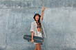 © puhhha - Skater Girl With Skateboard Portrait. Asian Teenager In Casual Outfit Posing Against Concrete Wall At Skatepark. Urban Subculture And Skateboarding As Lifestyle Of Active Teens In City.