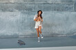 © puhhha - Portrait Of Skater Girl In Skatepark Having Fun. Female Teenager In Urban Outfit With Skateboard Against Concrete Wall. Summer Skateboarding With Modern Sport Equipment As Part Of Active Lifestyle.