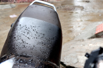 Sticker - Closeup of a black motorcycle seat covered in raindrops outdoors during daylight