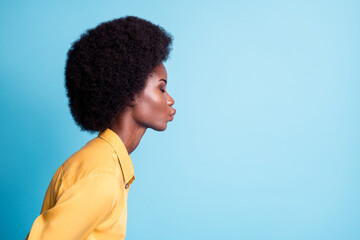 Wall Mural - Closeup portrait side profile photo of dark skin big volume hairstyle lady send air kiss blow empty space quarantined boyfriend wear yellow shirt isolated blue color background