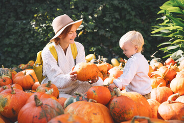 Happy mother and child at pumpkin patch outdoors.