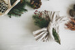 © sonyachny - Stylish christmas gift flat lay. Present wrapped in linen fabric decorated with natural fir branch on white rustic table background with pine cones and herbs. Zero waste winter holidays