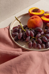 Wall Mural - juicy fresh peaches and grapes on a plate on a light background