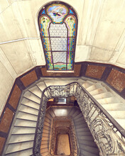 Beautiful Rectangular Spiral Staircase With Black Railings And Amazing Stained Glass Window Down View