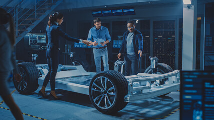 Poster - Female Project Manager Talks about Electric Car Prototype with Her Team of Engineers, Showing Chassis, Explaining Sustainability and Ecological Efficiency of the Engine