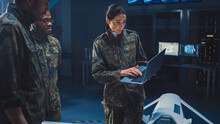 International Team Of Military Personnel Have Meeting In Top Secret Facility, Female Leader Holds Laptop Computer Talks With Male Specialist. People In Uniform On Strategic Army Meeting