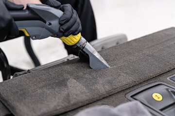 Poster - Man car detailing studio worker washing car upholstery with vacuum washer