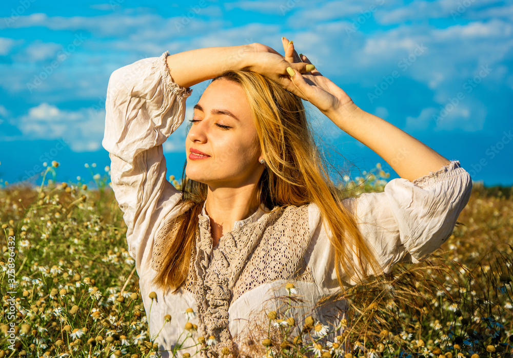girl with flying long hair stands in field enjoying the sun and good ...