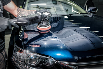 Man with orbital polisher polishing car.