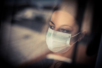 Woman wearing a surgical mask by a window