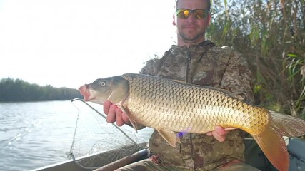 Wall Mural - Man with carp fish. Young angler holds Carp fish being on the river