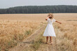 © Елена Лавринович - A beautiful woman in a white dress and a straw hat walks in the field.