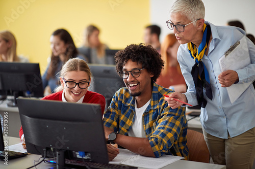 Fotografía Teacher looking pupils task on theirs computer