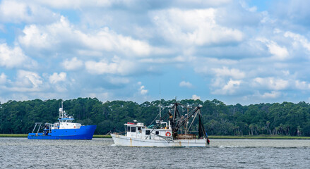 A Shrimp Boat Trawler Heading to Sea for a Day of Fishing  next to a Research Vessel in Savannah Georgia