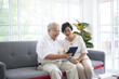 © tonefotografia - A happy senior Asian couple is using tablet and talking with family on webcam at home, retirement concept.